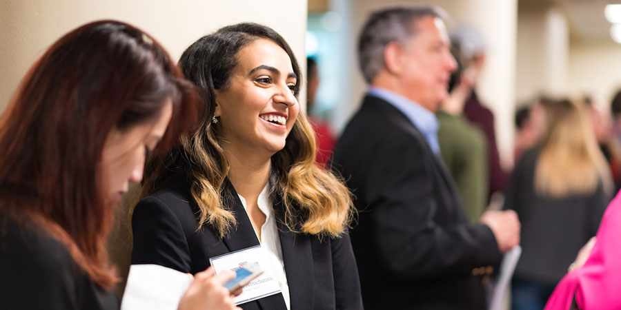 in focus, college-aged girl, laughing, in room of out of focus people